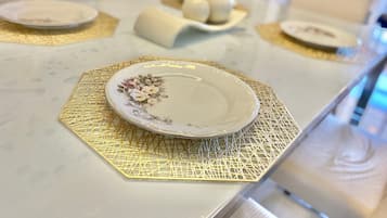 Una mesa de comedor con un plato floral, un posavasos dorado y un tazón de huevos.