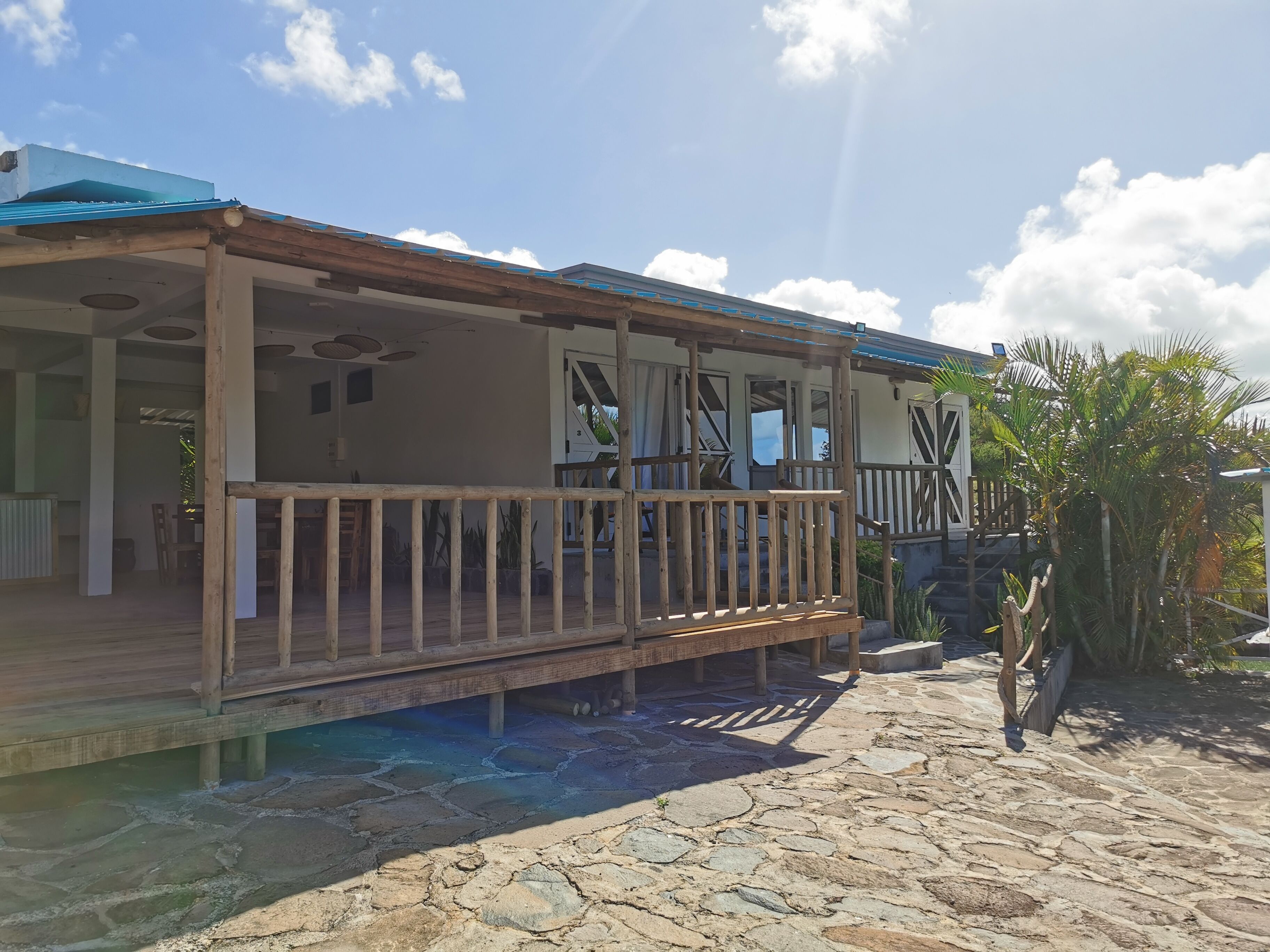 A wooden building with a balcony, stone flooring, and a clear sky.