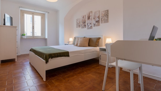 A bedroom with a bed, bedside tables, a desk, and a chair. - Il Papiro Apartment by Wonderful Italy (Turin)