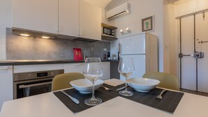 A modern kitchen with a dining table set for two, featuring two wine glasses and bowls. - Il Papiro Apartment by Wonderful Italy (Turin)