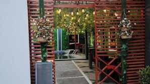 A pathway leading to a pool area with a wooden fence and hanging baskets of flowers. - Opt Wood Hotels  (Benin City)