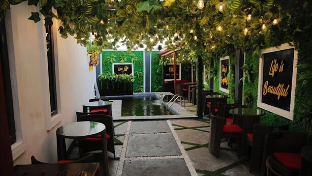 An indoor patio area with tables and chairs, a small pool, and greenery overhead. - Opt Wood Hotels  (Benin City)