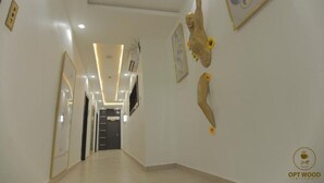 A hallway with a modern design, featuring a central light fixture, a framed picture on the wall, and a logo for 'OPT WOOD BISTRO' in the bottom right corner. - Opt Wood Hotels  (Benin City)