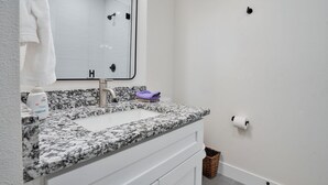 Une salle de bain avec un lavabo blanc, un comptoir en granit et un miroir.