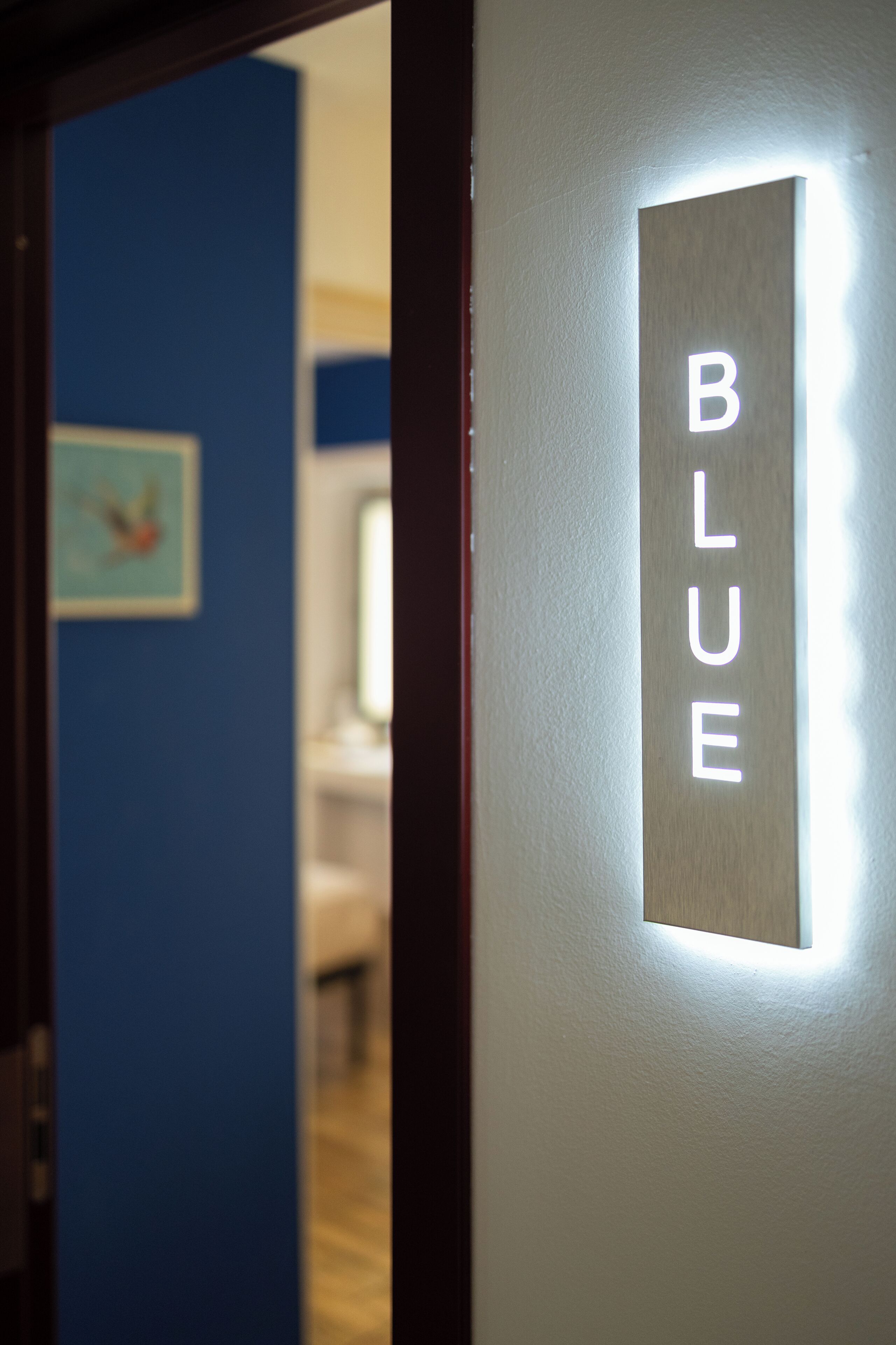 A hallway with a sign reading "BLUE" and a painting on the wall.