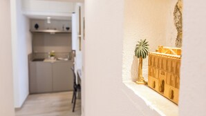 A narrow hallway with a kitchen area on the left and a small model display case on the right. - Barlaman Luxury Rooms (Palermo)