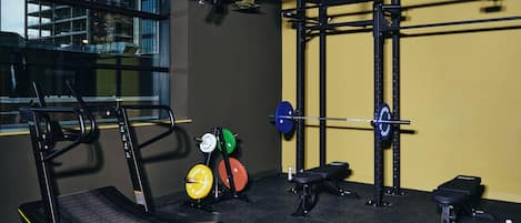 A gym with a treadmill, weightlifting equipment, and a bench.