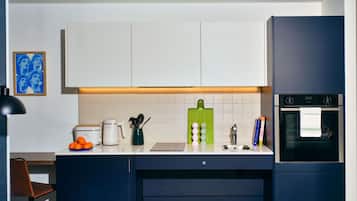 A modern kitchen with white cabinets, a green cutting board, and a built-in oven.