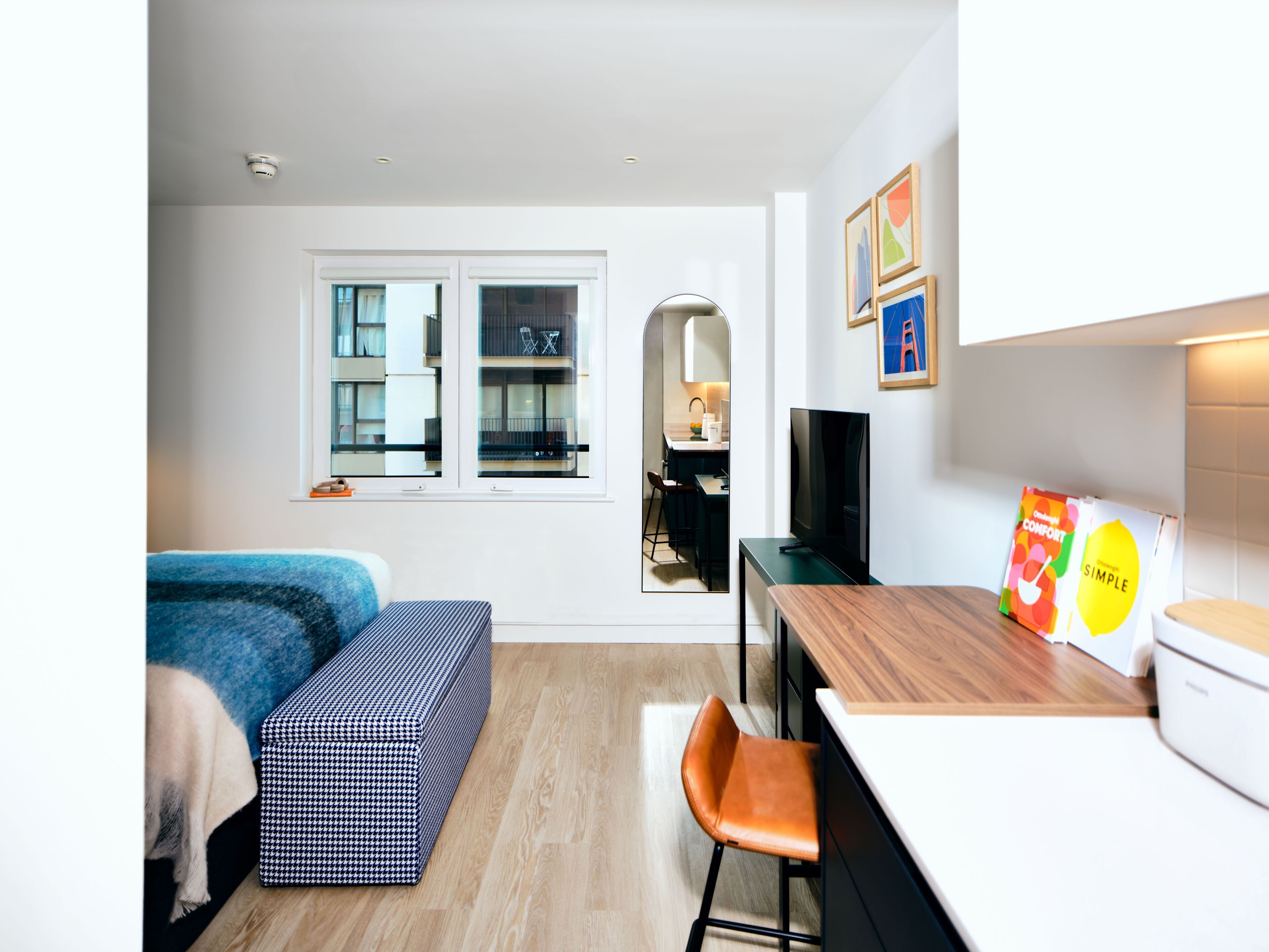 A compact living space with a sofa, a small dining area, a TV, and a kitchen counter.