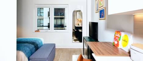 A compact living space with a sofa, a small dining area, a TV, and a kitchen counter.