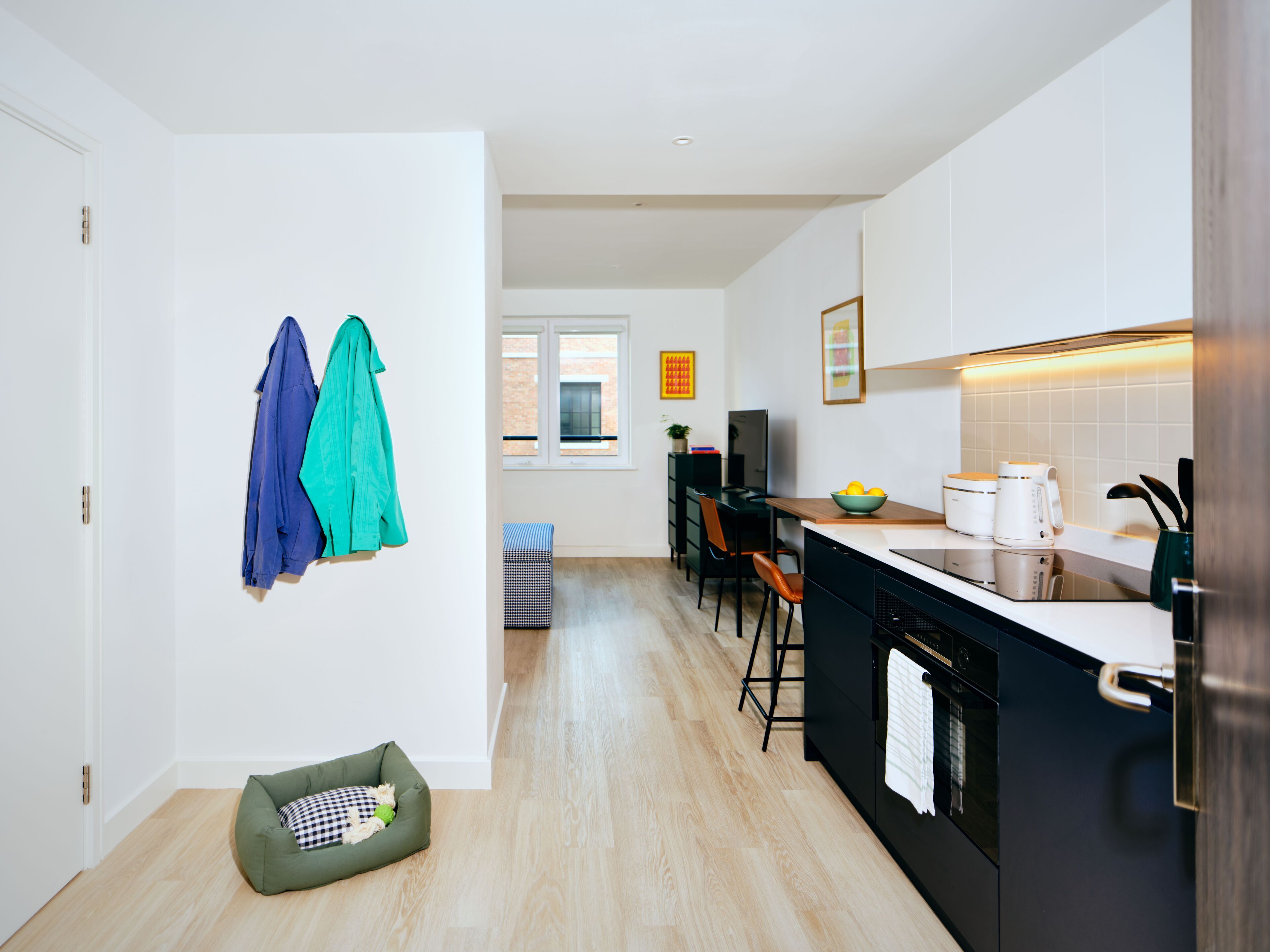 A modern kitchen with a dining area, a small seating space, and a view of the outside.