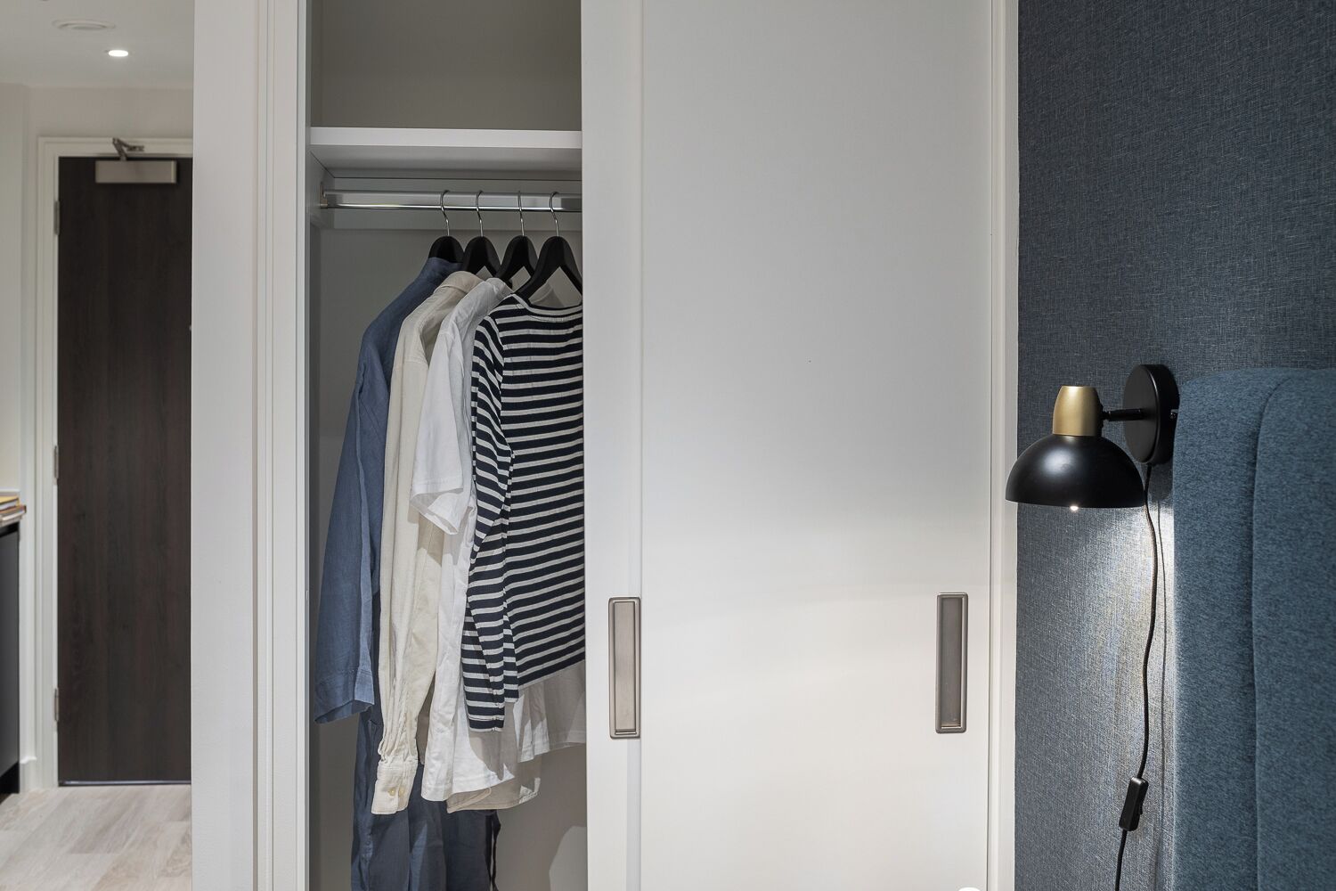 Ein begehbarer Kleiderschrank mit Kleiderstangen und einer Wandleuchte.