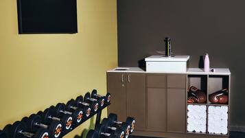 A gym with a row of dumbbells, a sink, and a cabinet with folded towels.