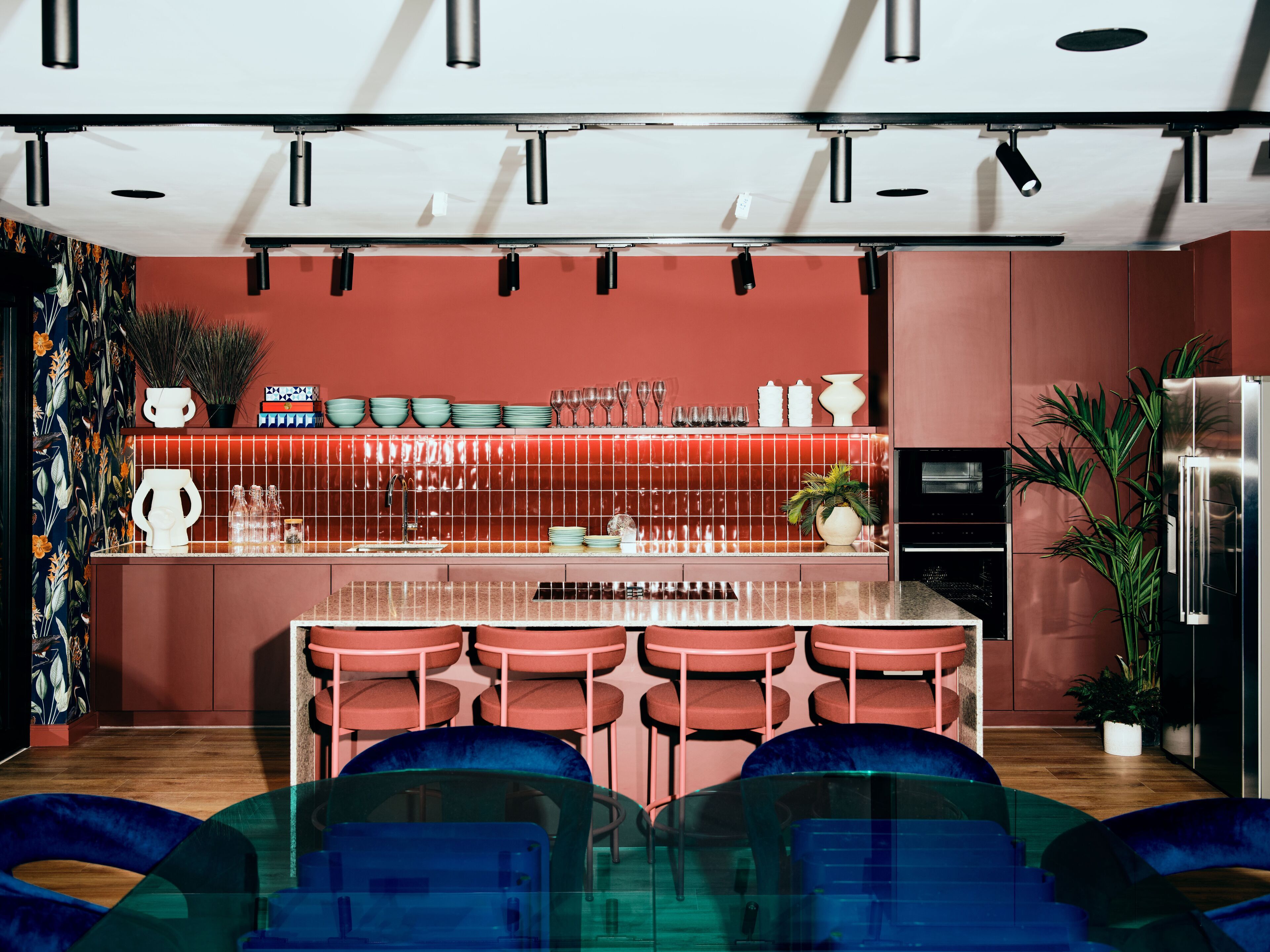 A modern kitchen with a central island, bar stools, and a refrigerator.