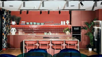 A modern kitchen with a central island, bar stools, and a refrigerator.