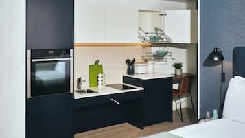 Eine kleine Küche mit Backofen, Spüle und einer Essecke mit einem Stuhl.