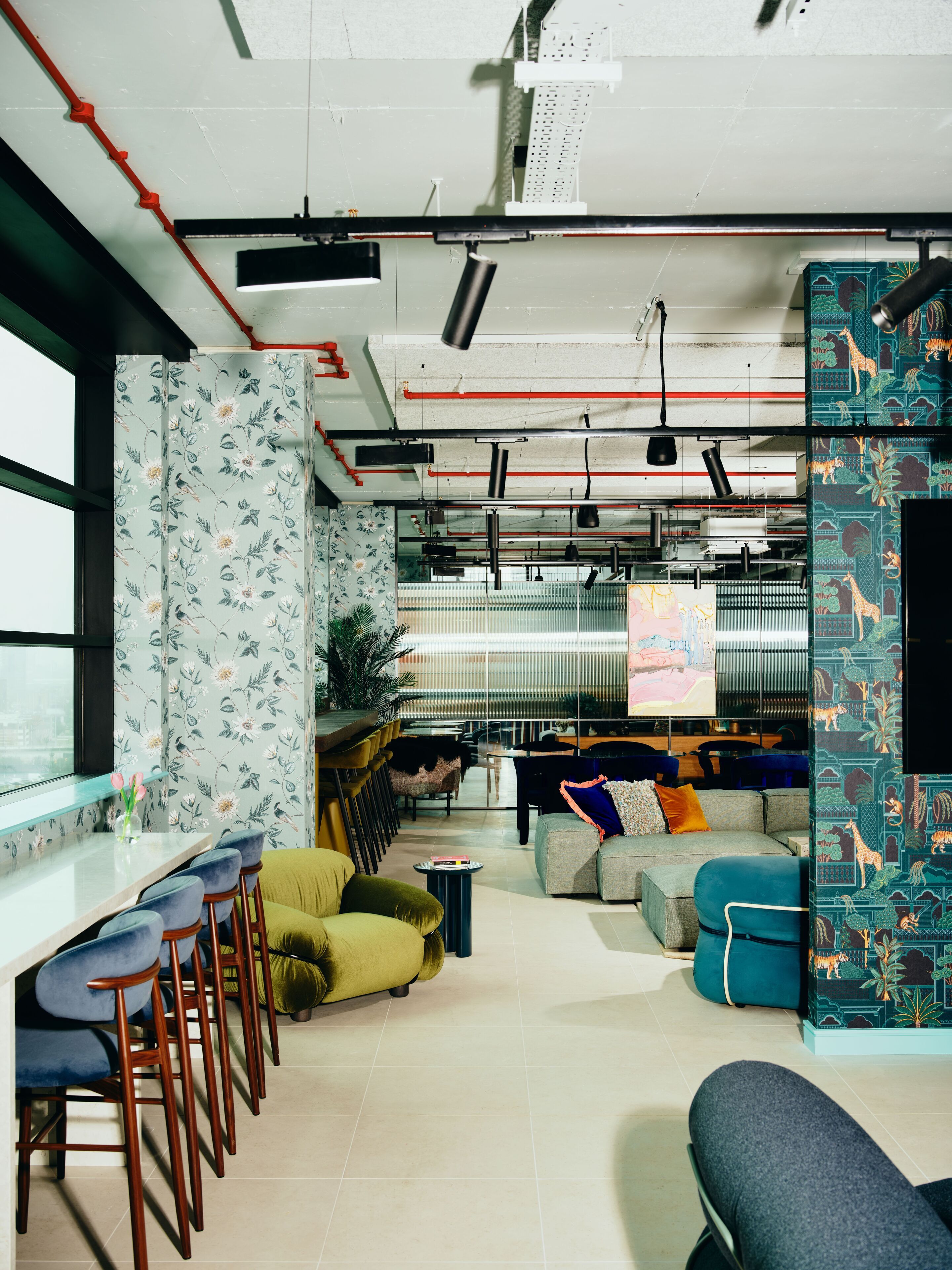 A modern office space with a long table, multiple chairs, a sofa, and a patterned wall.
