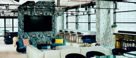 Een moderne lounge met een grote flatscreen-tv, comfortabele zithoeken en een bar.