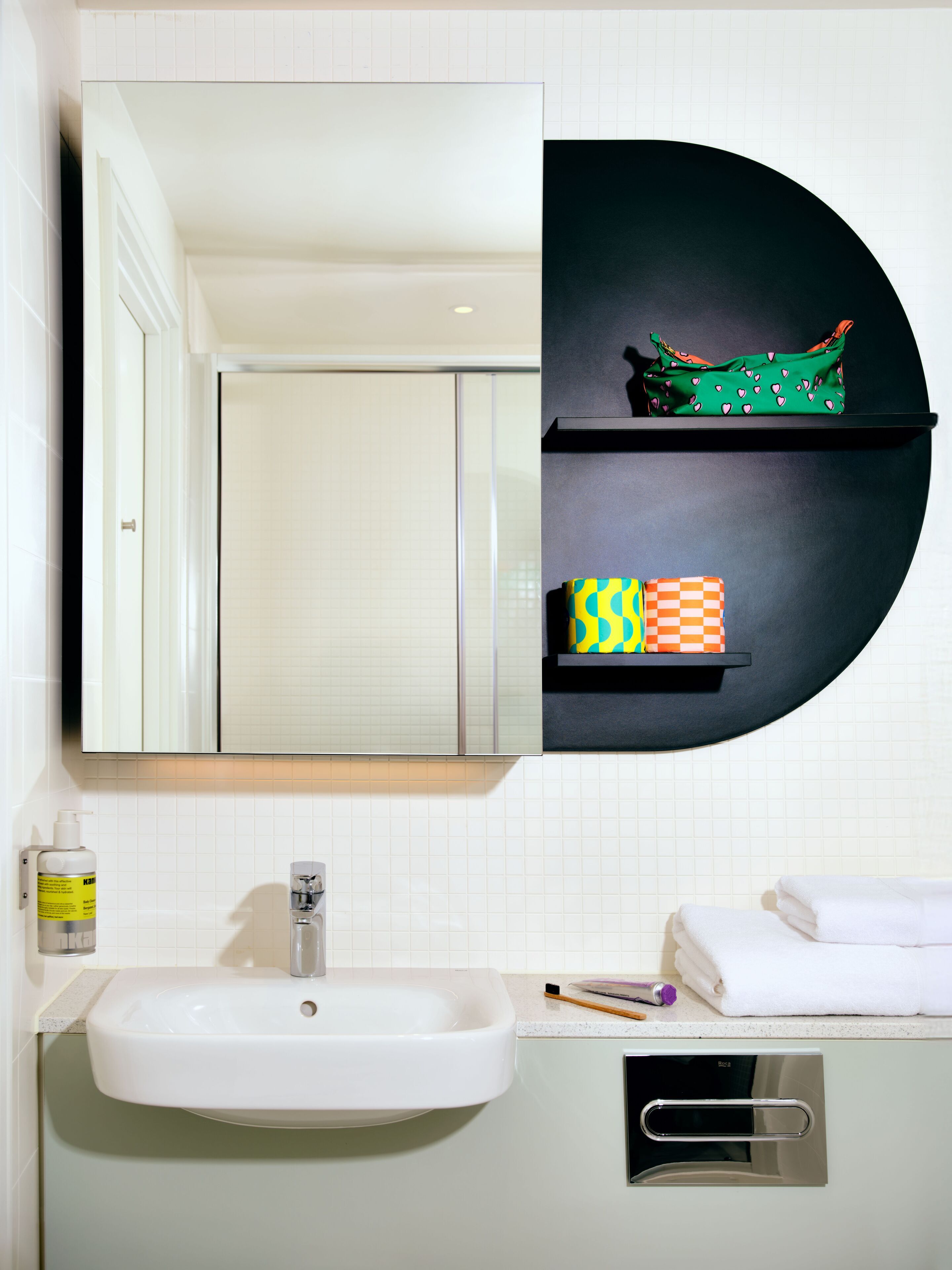 A bathroom with a sink, mirror, and shelves with toiletries.