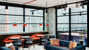A modern interior with seating areas, tables, and large windows offering city views. - Vertus Edit Canary Wharf (London)