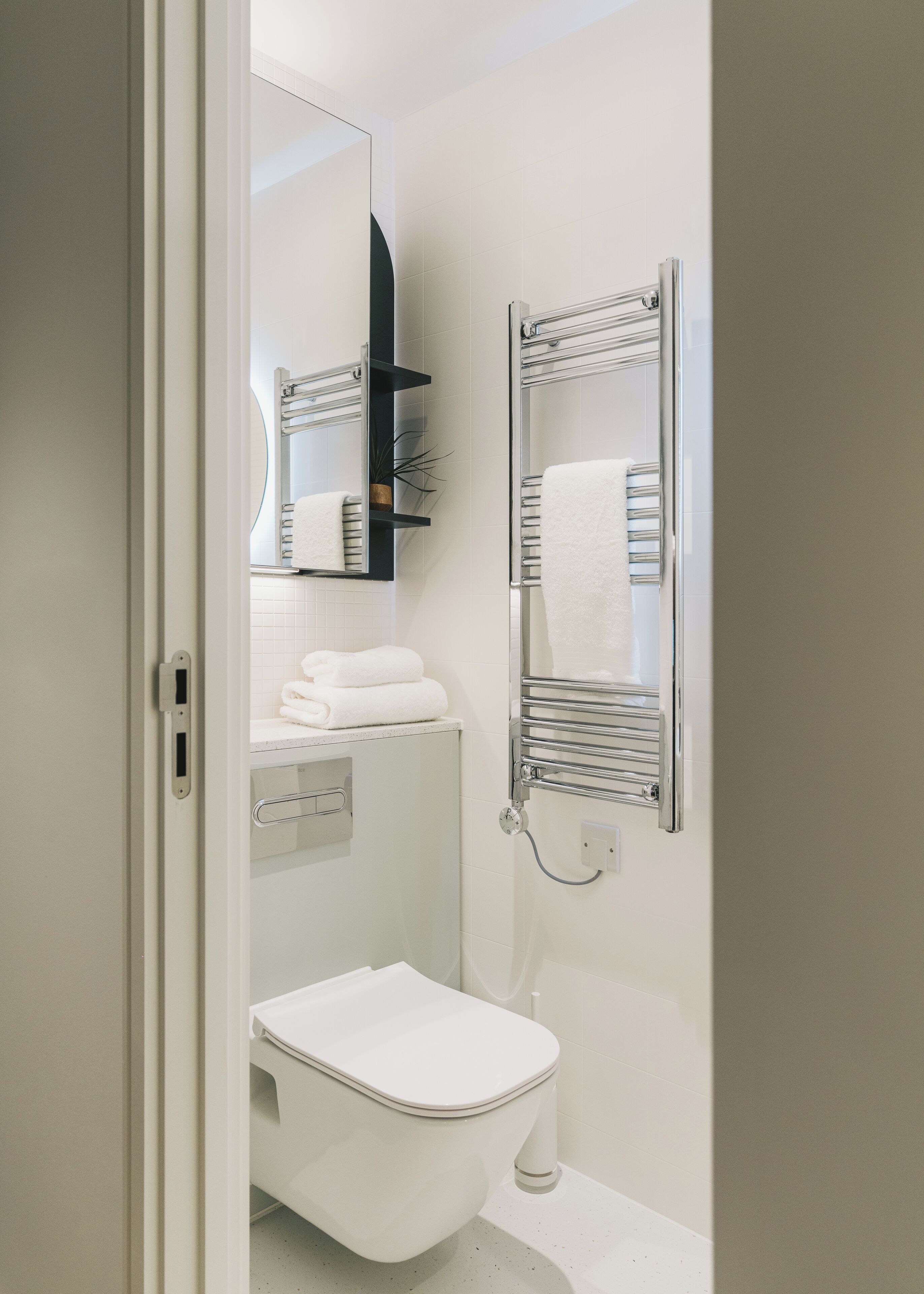 Un baño moderno con inodoro, lavabo, espejo y toalleros.