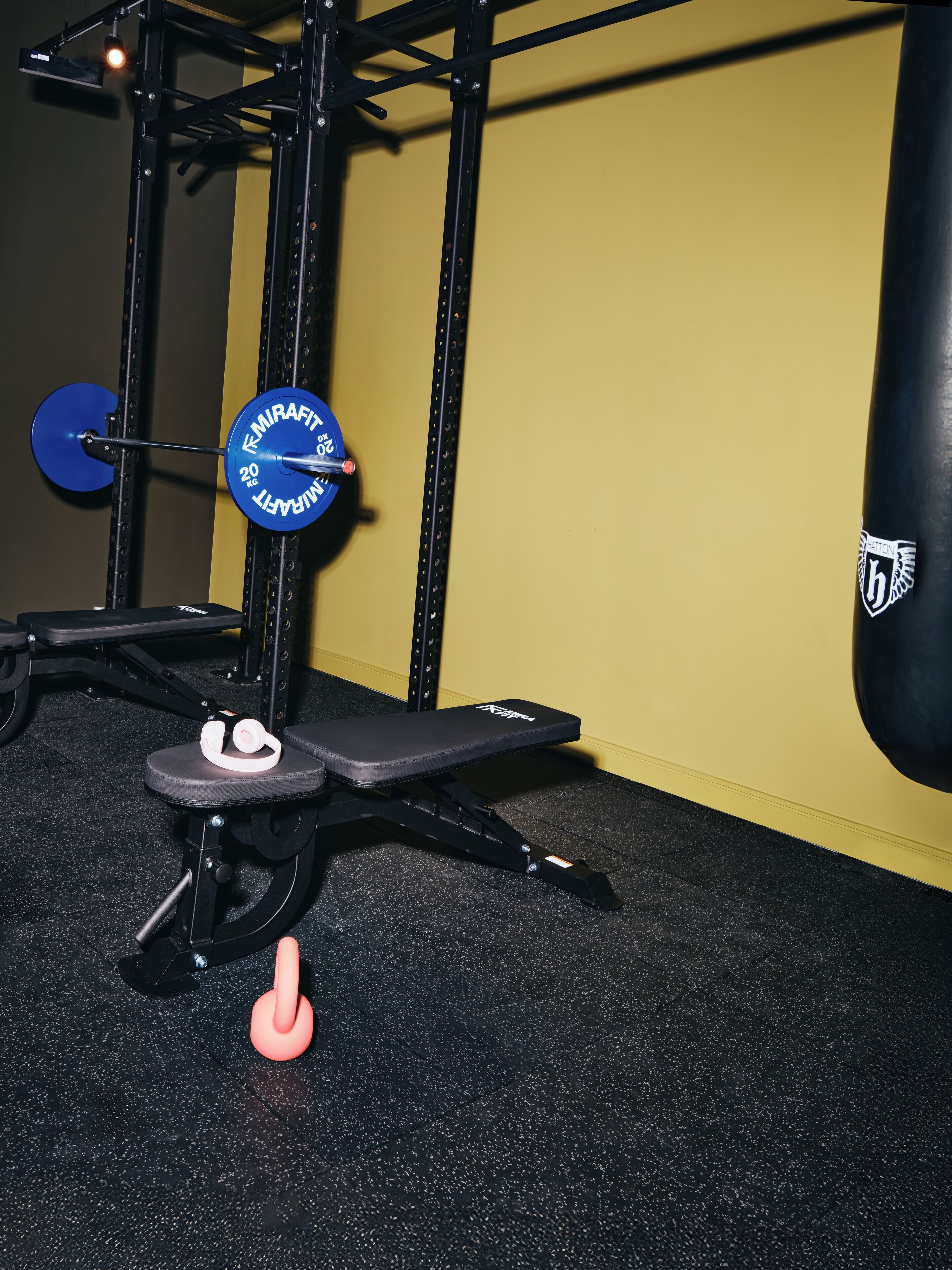 A gym with a squat rack, bench, and a punching bag.