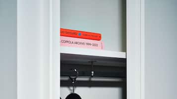 Un placard avec deux cintres, un rose et un bleu, et deux livres posés sur le dessus.