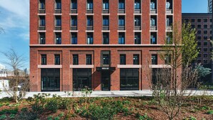 A multi-story brick building with a modern facade, large windows, and a visible entrance with a sign. - Vertus Edit Canary Wharf (London)