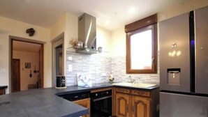 A modern kitchen with a built-in oven, a stainless steel refrigerator, and wooden cabinets. - Capucine's house (Les Moutiers-en-Cinglais)