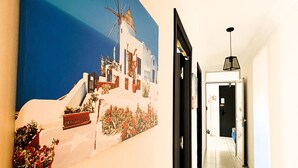 A hallway with a large painting of a coastal scene, a tiled floor, and a door at the end. - Confort Moderne in the heart of Salé, near train station and airport (Rabat- Sale')