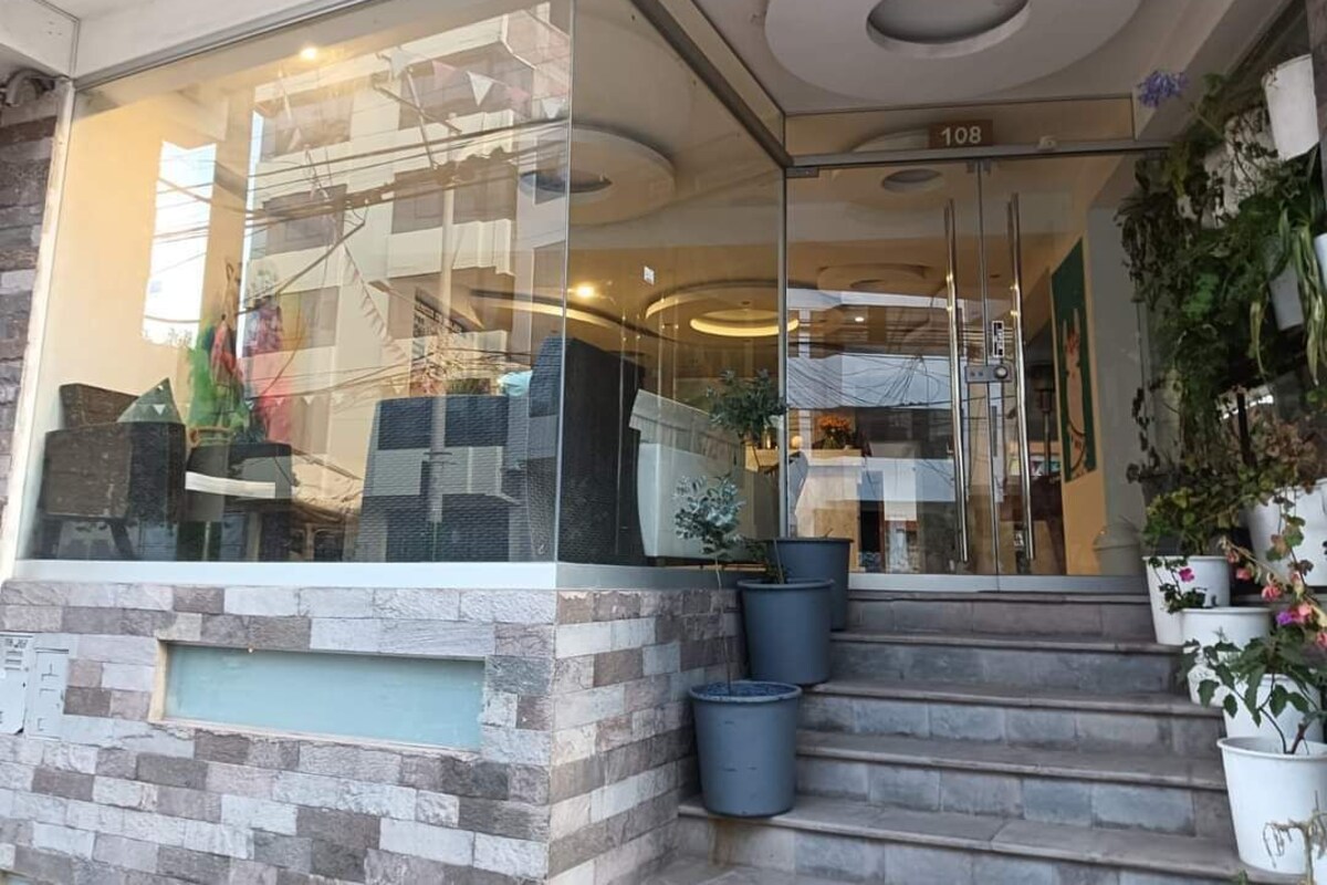 A hotel entrance with a glass facade, a stone facade, and a number '108' above the door.