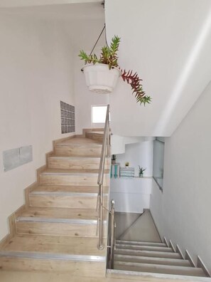 A staircase with wooden steps and a metal railing, leading to a landing with a hanging plant. - Tours Machu Picchu Perù Hotel (Cusco)