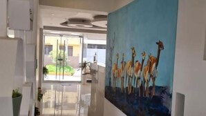 A hallway with a large painting of giraffes on the wall, a glass door leading to an outdoor area, and a white interior. - Tours Machu Picchu Perù Hotel (Cusco)