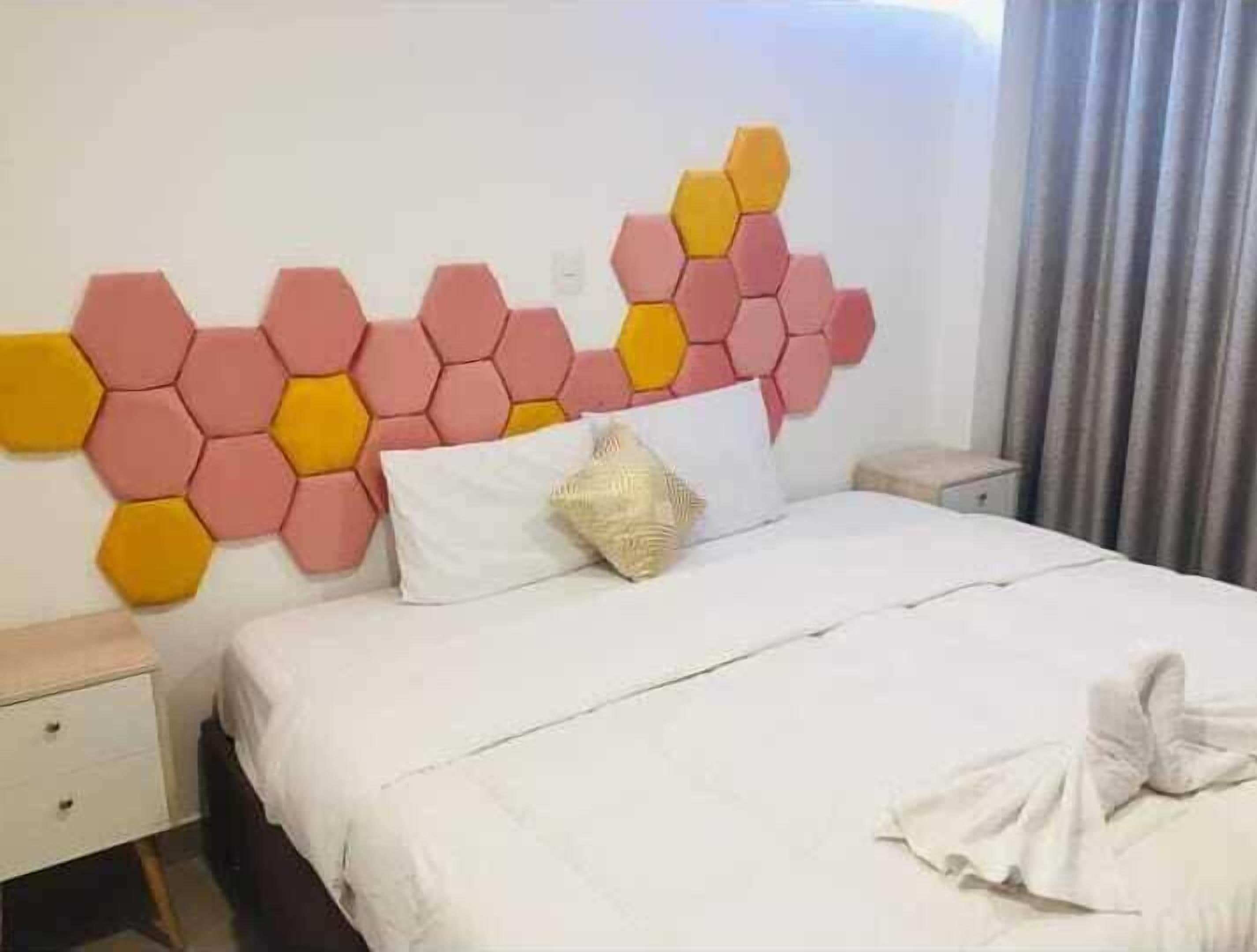 Una habitación de hotel con una cama, una mesita de noche y una pared con diseño de panal.