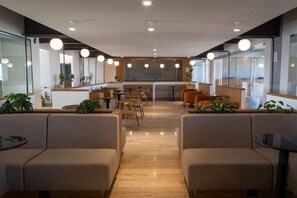Relax in a contemporary lounge area with comfortable sofas and tables, surrounded by glass partitions and pendant lights.