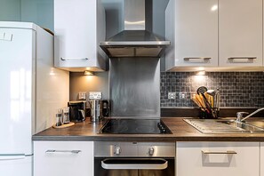 Eine moderne Küche mit Edelstahlgeräten, einer schwarzen Fliesenspiegel und einem eingebauten Backofen.