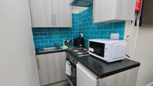 A compact kitchen with teal backsplash, a microwave, and a sink. - LHR Studio 4 - Coventry (Coventry)