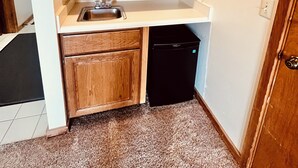 Una cucina compatta con mobili in legno, un forno a microonde, un lavello e una lavastoviglie.