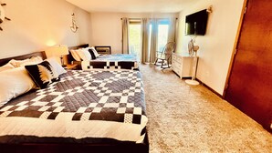 Una camera d'albergo con due letti, una televisione a parete, una sedia e un comò.