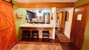 Una cucina con isola centrale, sgabelli da bar e soffitto in legno.