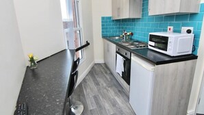 A compact kitchen with a black countertop, a white microwave, and a sink. - LHR Studio 6 - Coventry (Coventry)