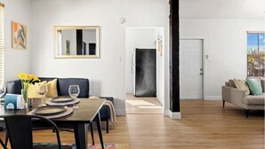 Zona d'estar àmplia amb taula de dinar per a dues persones, un sofà i un mirall gran a la paret.