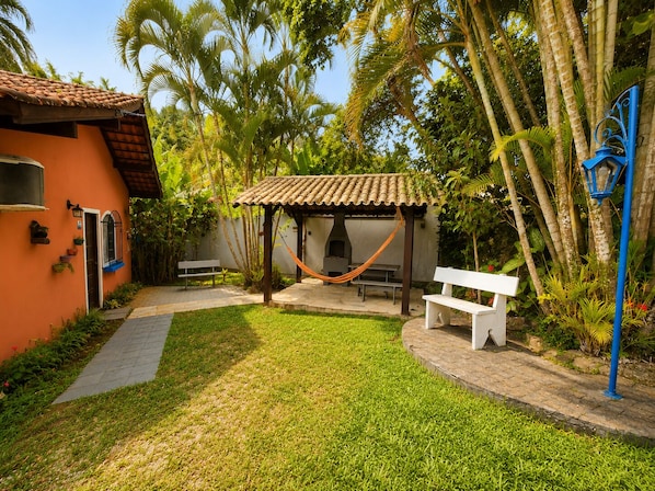 A patio area with a hammock, a barbecue grill, and a white bench.