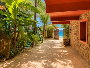 A pathway leading to a beach with a stone wall and a wooden structure.