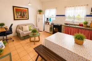 Una cocina compacta con comedor, un sofá, una mesa pequeña y un banco.