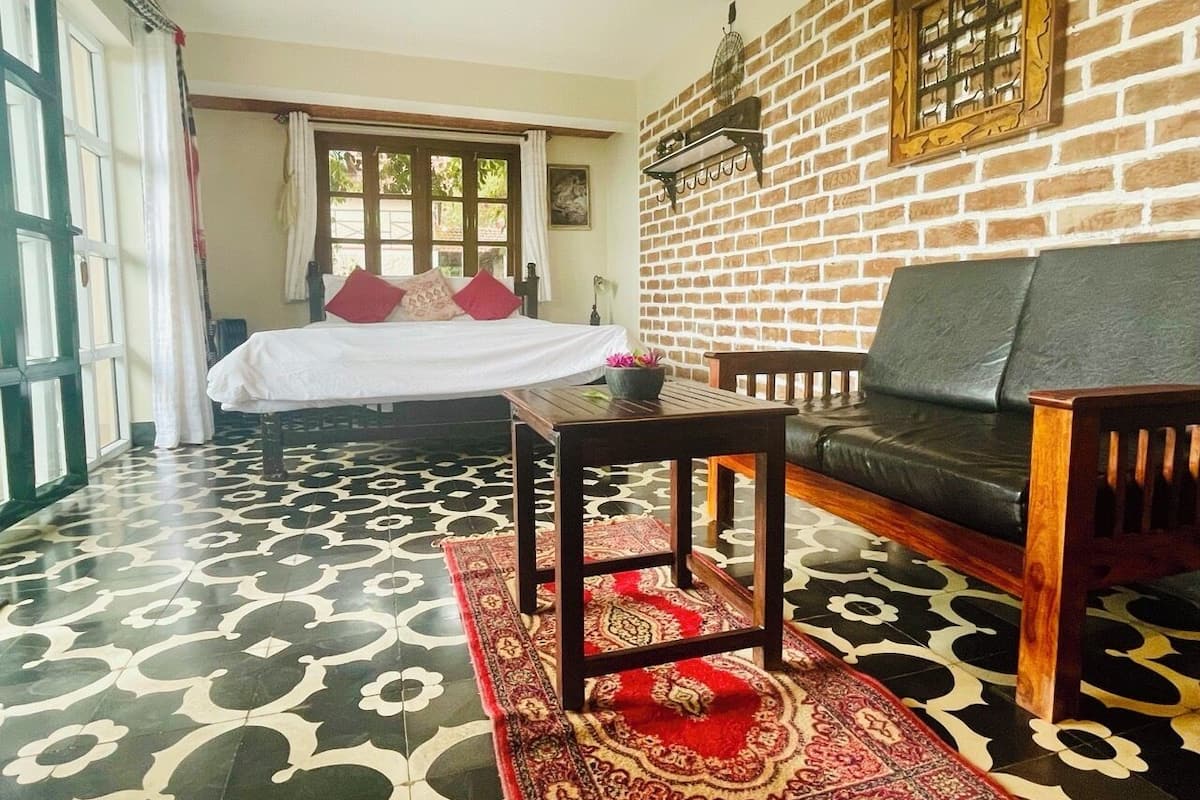 A room with a bed, a sofa, a table, and a patterned floor.