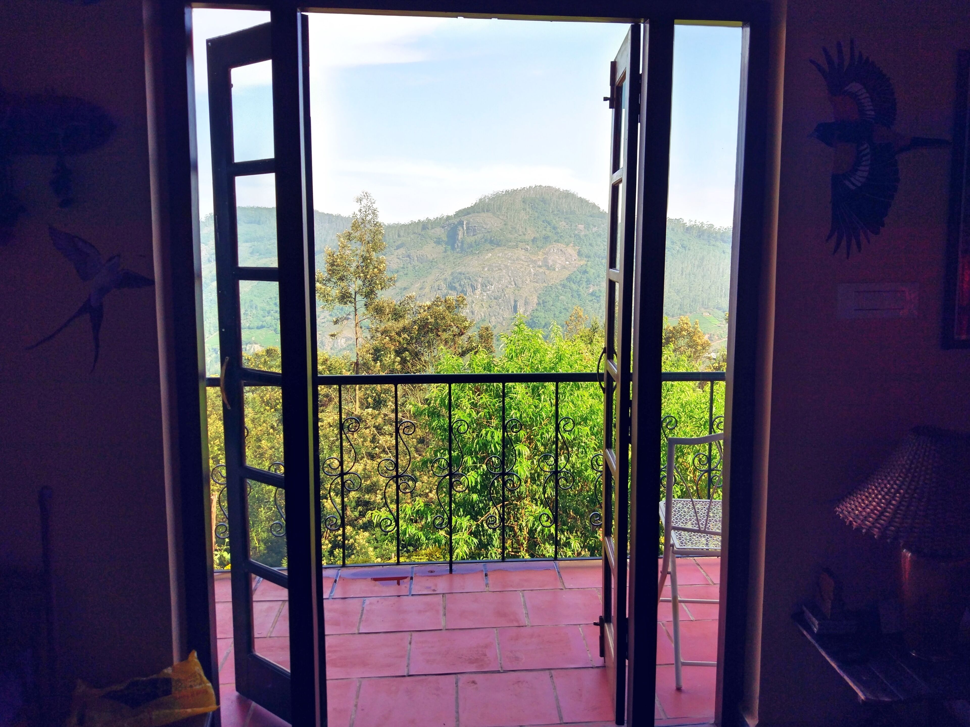 An open door leading to a balcony with a view of a mountainous landscape.