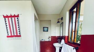 Et badeværelse med et mønstret gulv, toilet, vask og et vindue med udsigt.