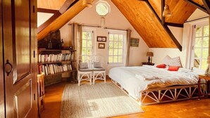 A cozy attic bedroom with a wooden ceiling, a bed, a bookshelf, and a desk. - Stumpfields (Ootacamund)