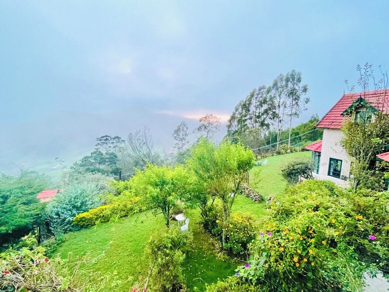 A lush green landscape with a small white building with a red roof.